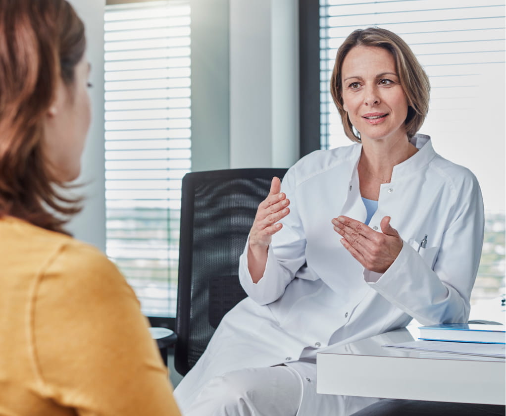 Female doctor in her office talking and gesturing to her patient.